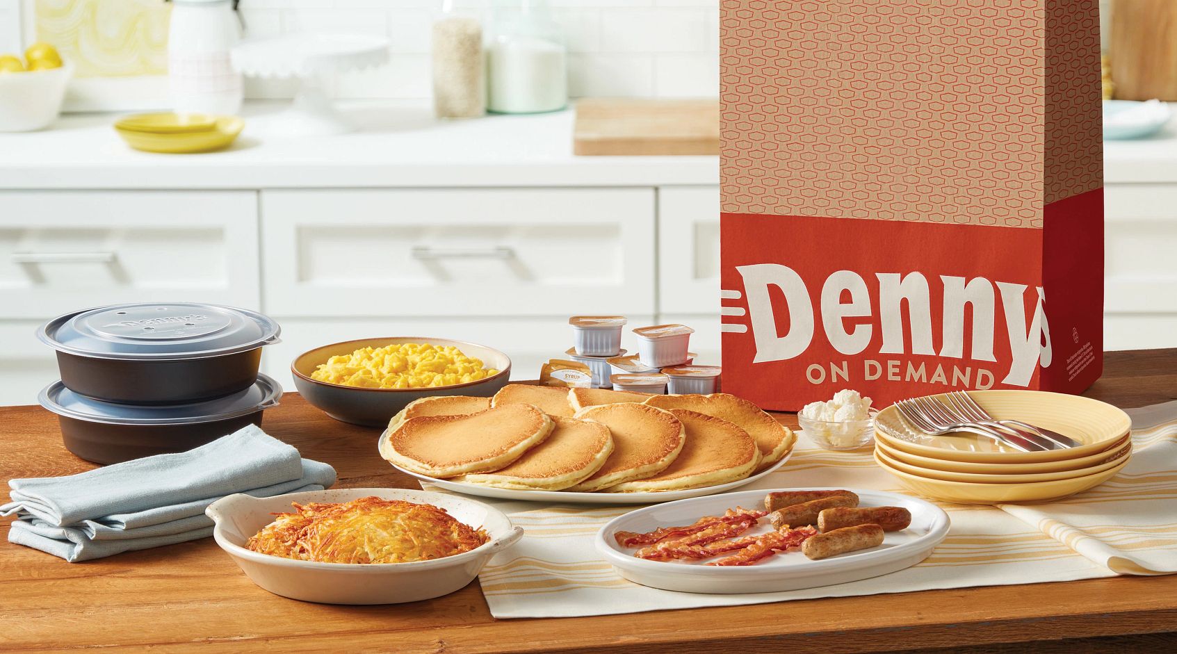 A table with breakfast foods and pancakes on it.
