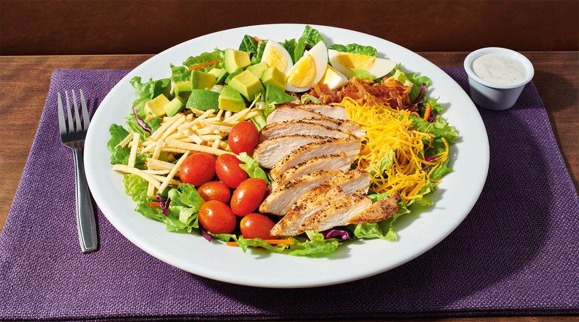 A plate of salad with chicken, tomatoes and avocado.