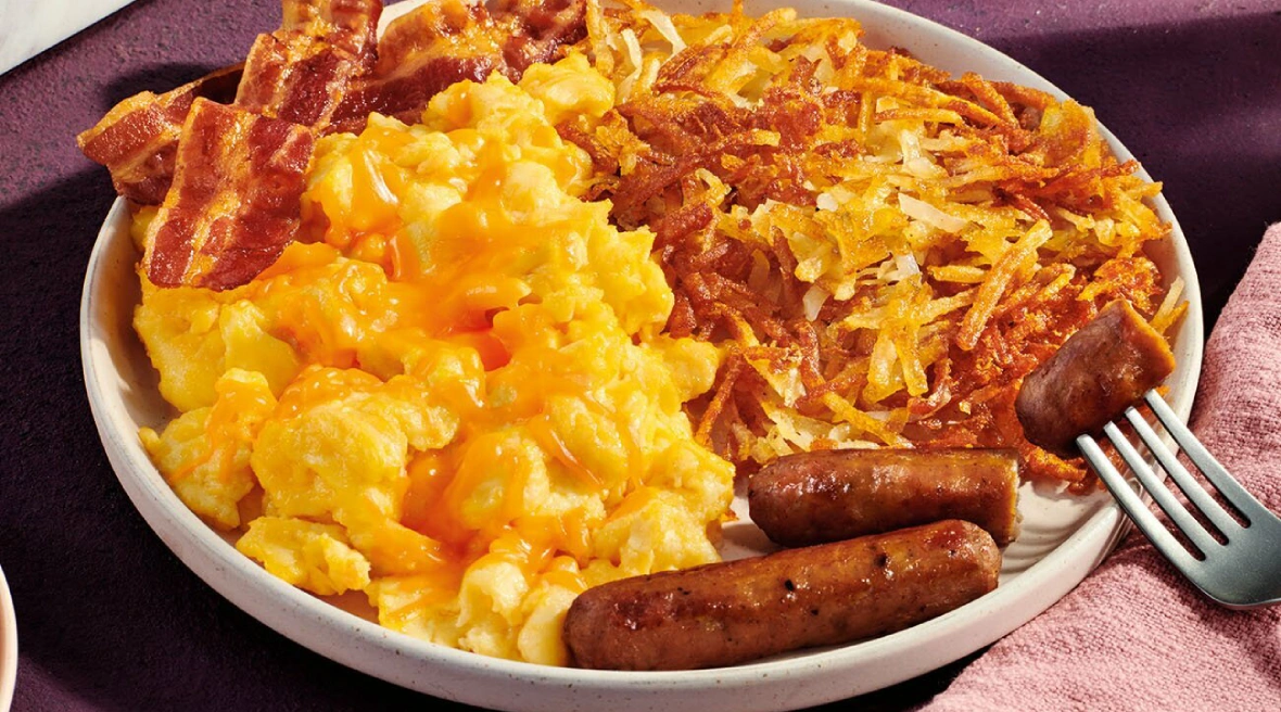 A plate of food with scrambled eggs, sausage and potatoes.